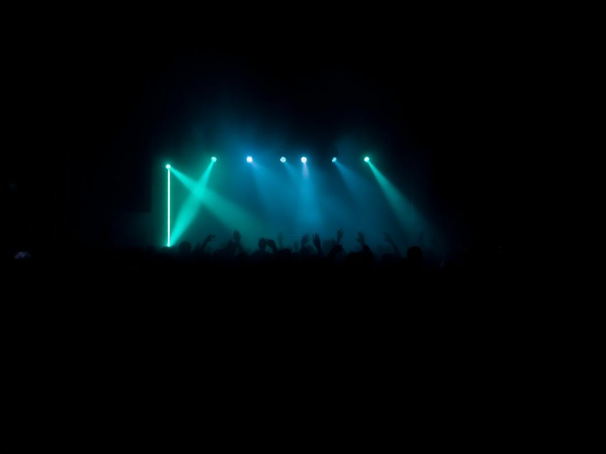Crowd silhouettes under teal and mint stage lights at a brand event